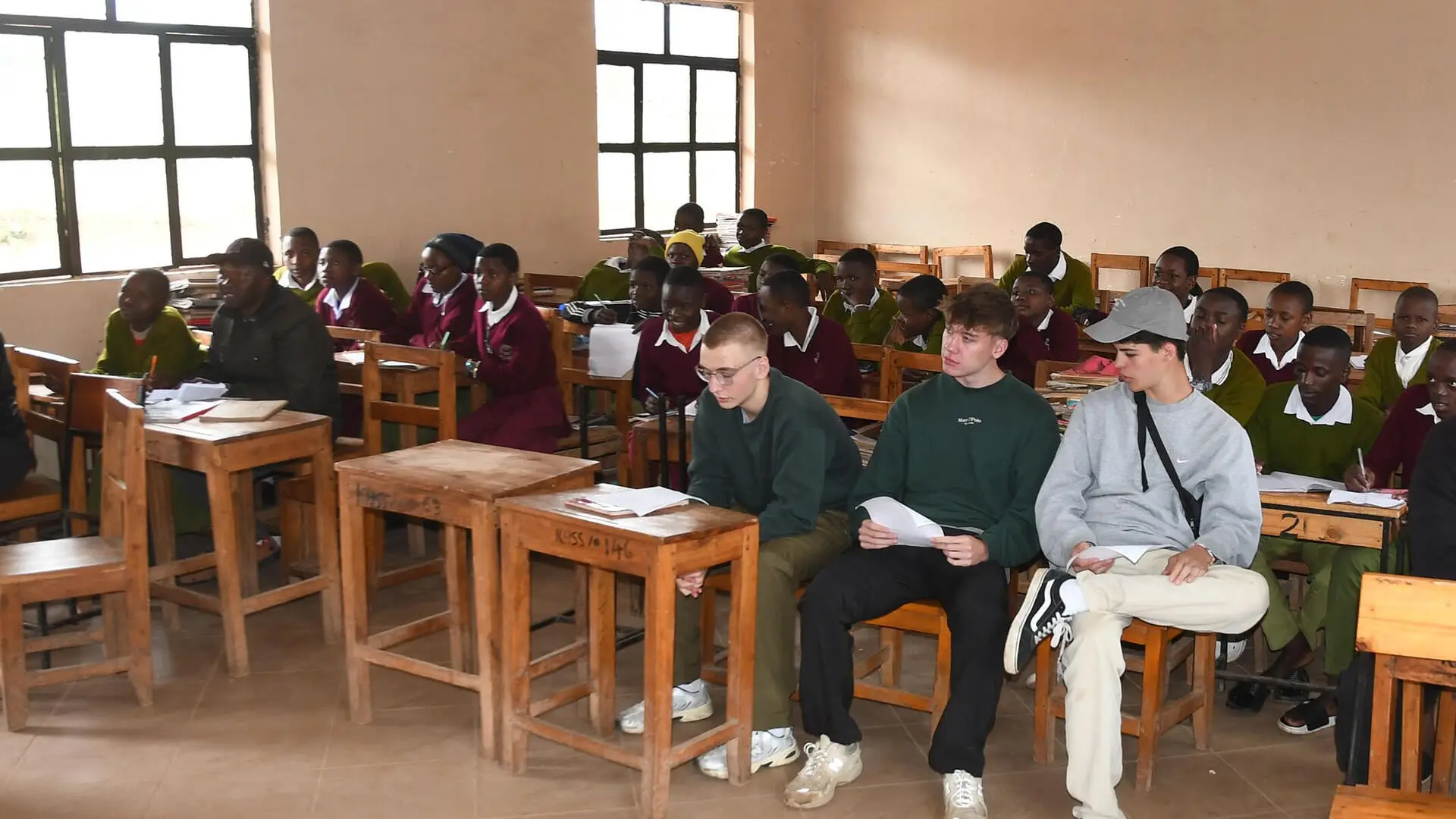 Drei bayerische Schüler sitzen im Klassenzimmer der Kihansi Secondary School in Mapanda, Tansania.