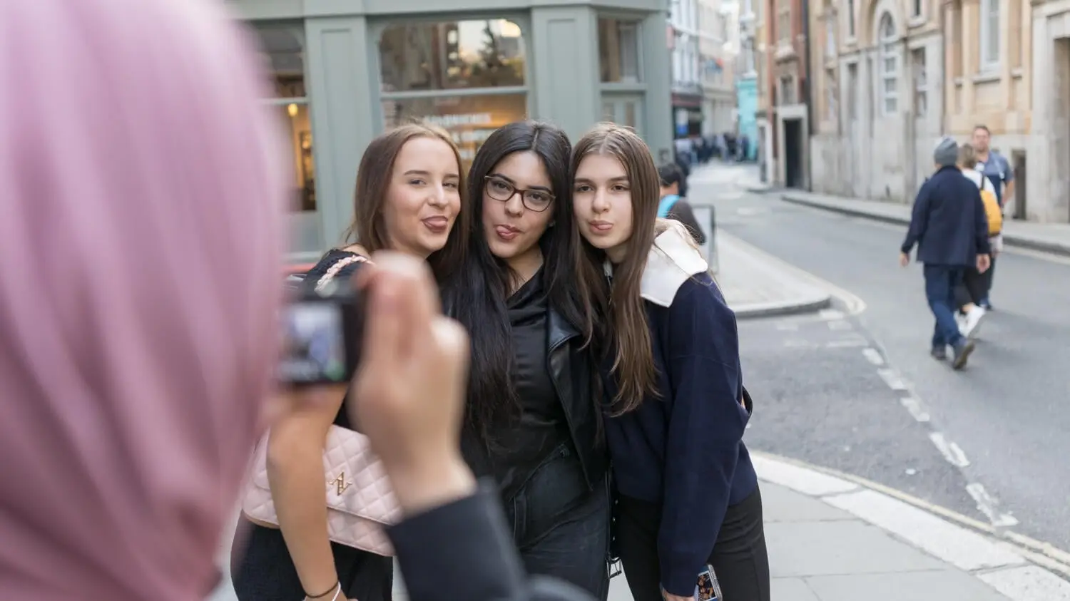 Drei Mädchen posieren in Großbritannien vor einer Handykamera